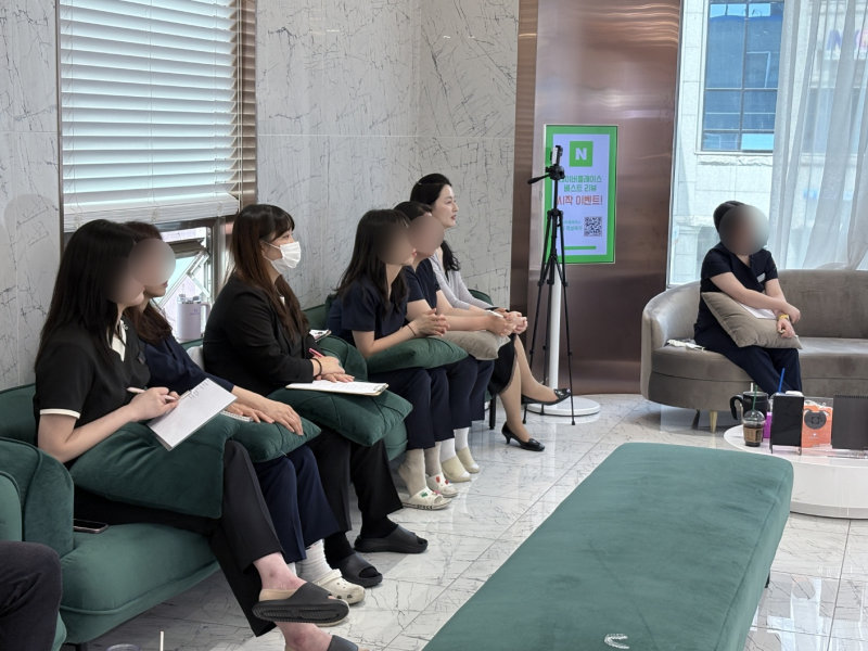 치과 대기실에서 여러 명이 앉아 발표를 듣고 있는 모습