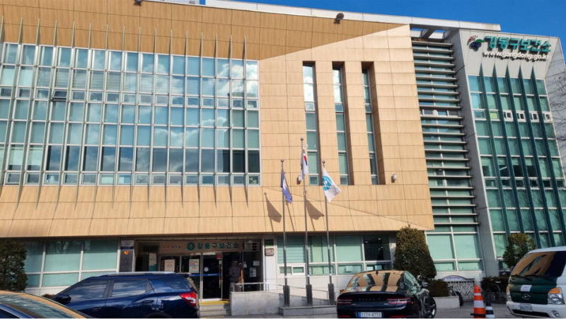 강동구 보건소 건물 외관, 여러 층의 창문과 깃발이 보임