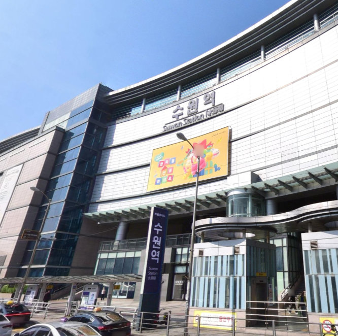 수원역 건물 외관 전경, 파란 하늘 아래 수원역 간판과 광고판이 보인다.